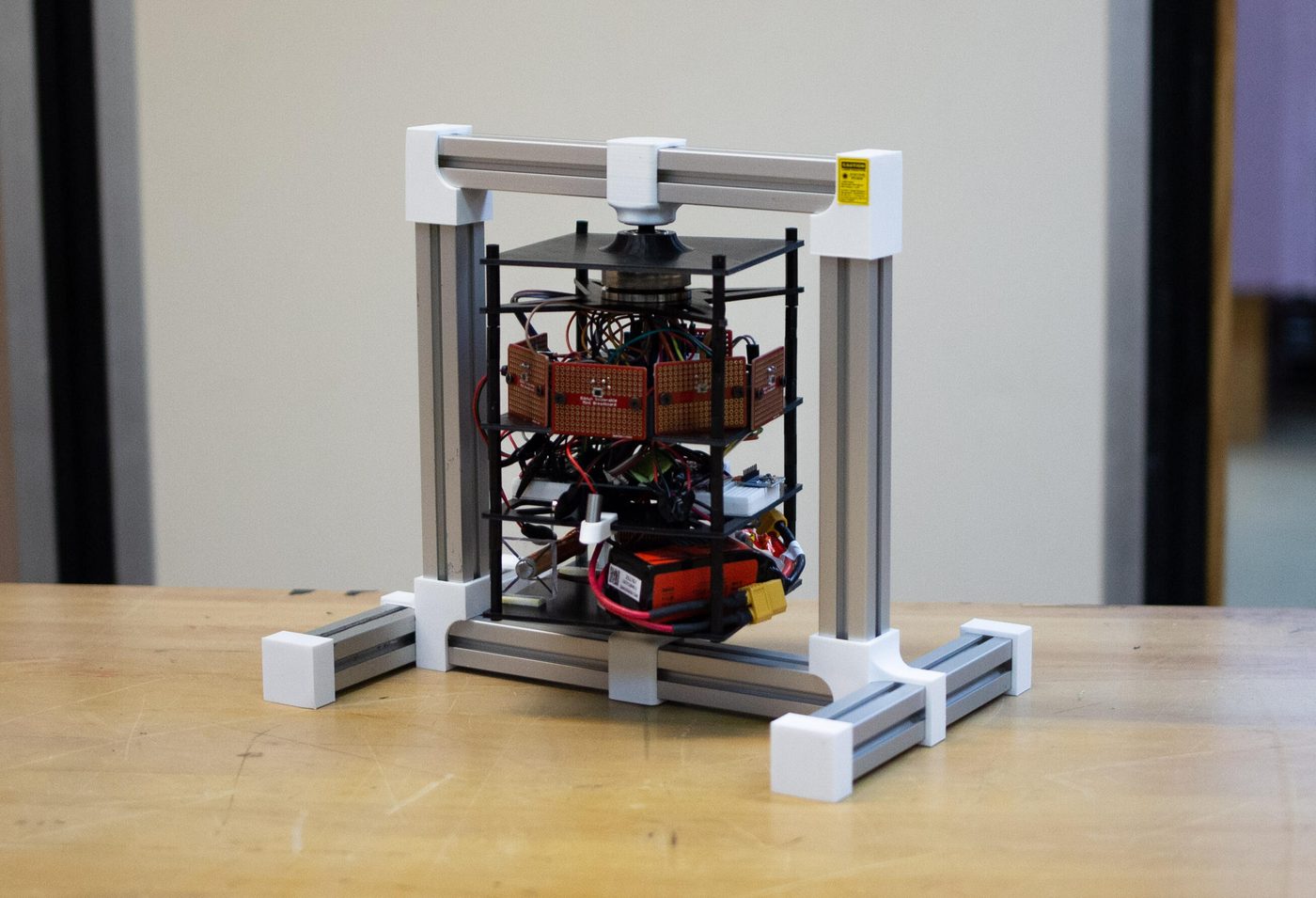 The single-axis ADCS prototype: an aluminum gantry supporting stacked equipment plates, breadboards and a reaction wheel.