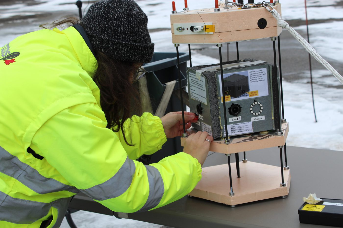 A team member arming the Horizon balloon payload outdoors in the snow before launch.
